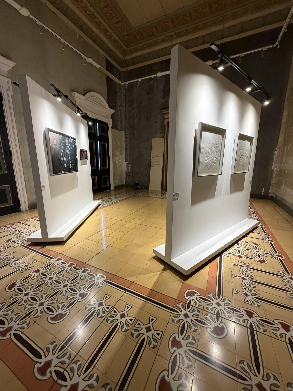 Montaje de la Sala 07 — Cuidar: vista del salón con muros expositivos, obras enmarcadas, texto de sala y piso decorado del Palacio Nacional
