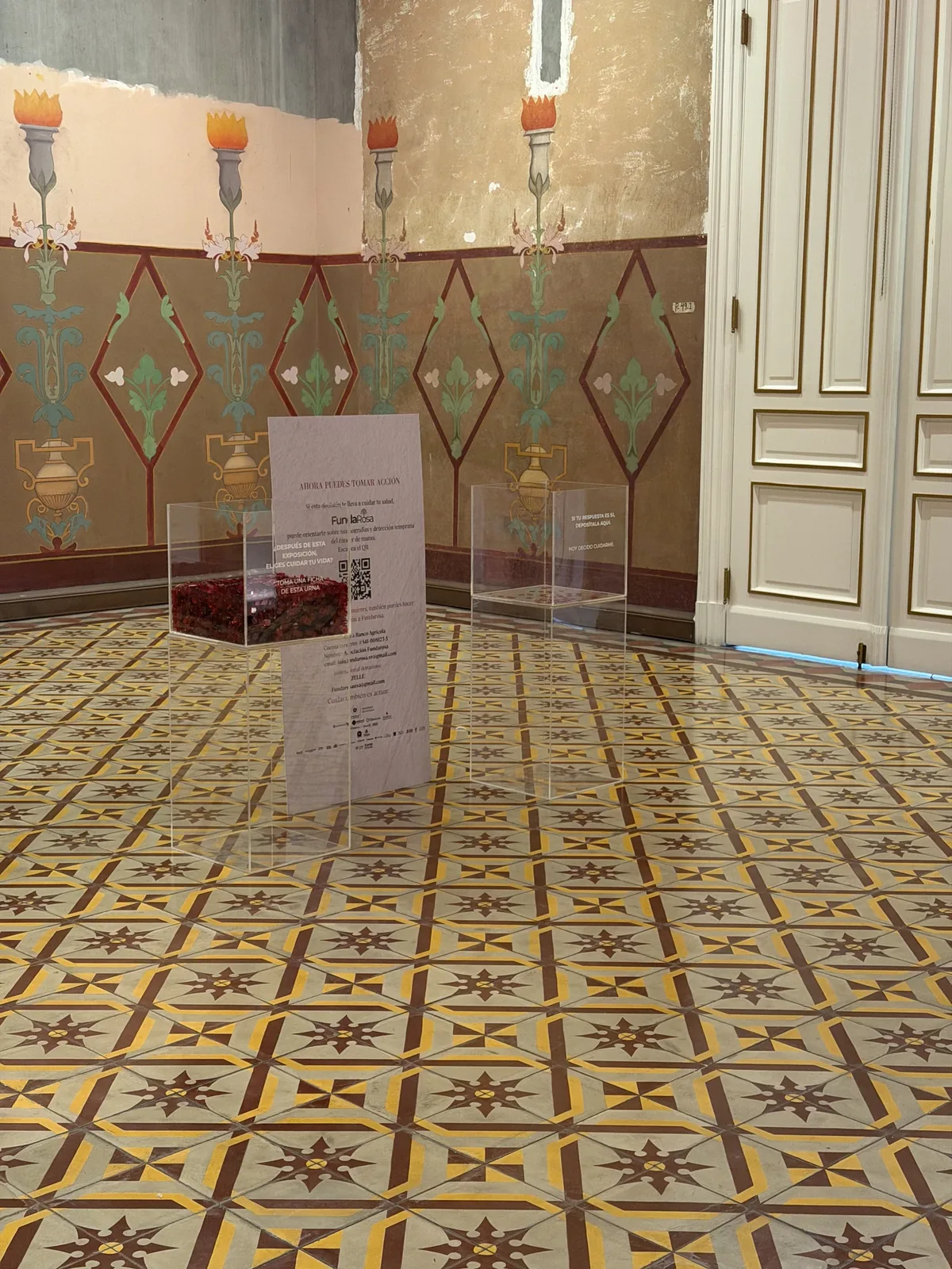 Montaje de la Sala 11 — Decisión: urnas acrílicas, panel central con código QR, piso de mosaico y decoración mural del Palacio Nacional