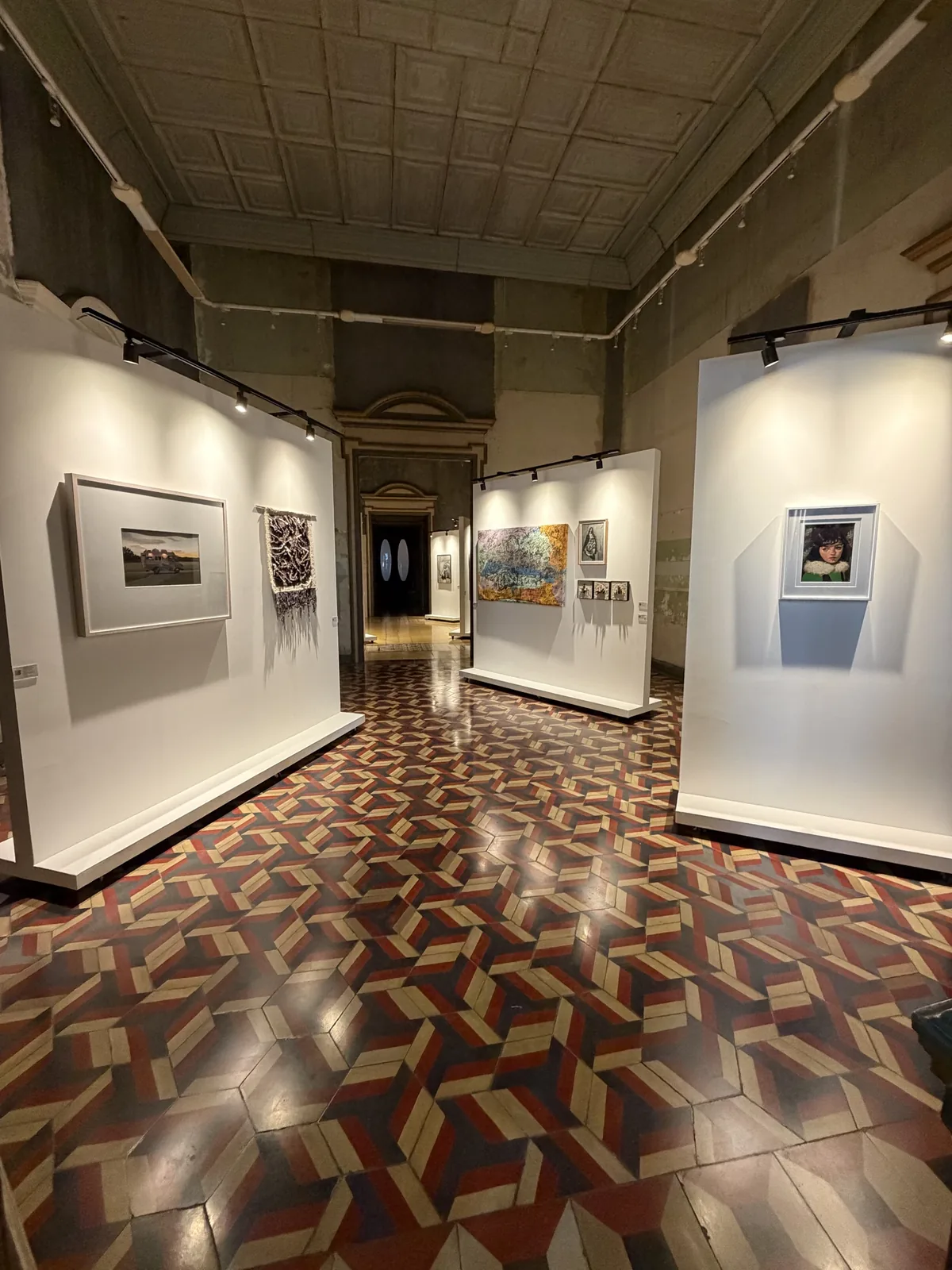 Montaje de la Sala 06 — Fragilidad: vista del salón con muros expositivos, obras enmarcadas y piso de mosaico hacia el fondo del recorrido