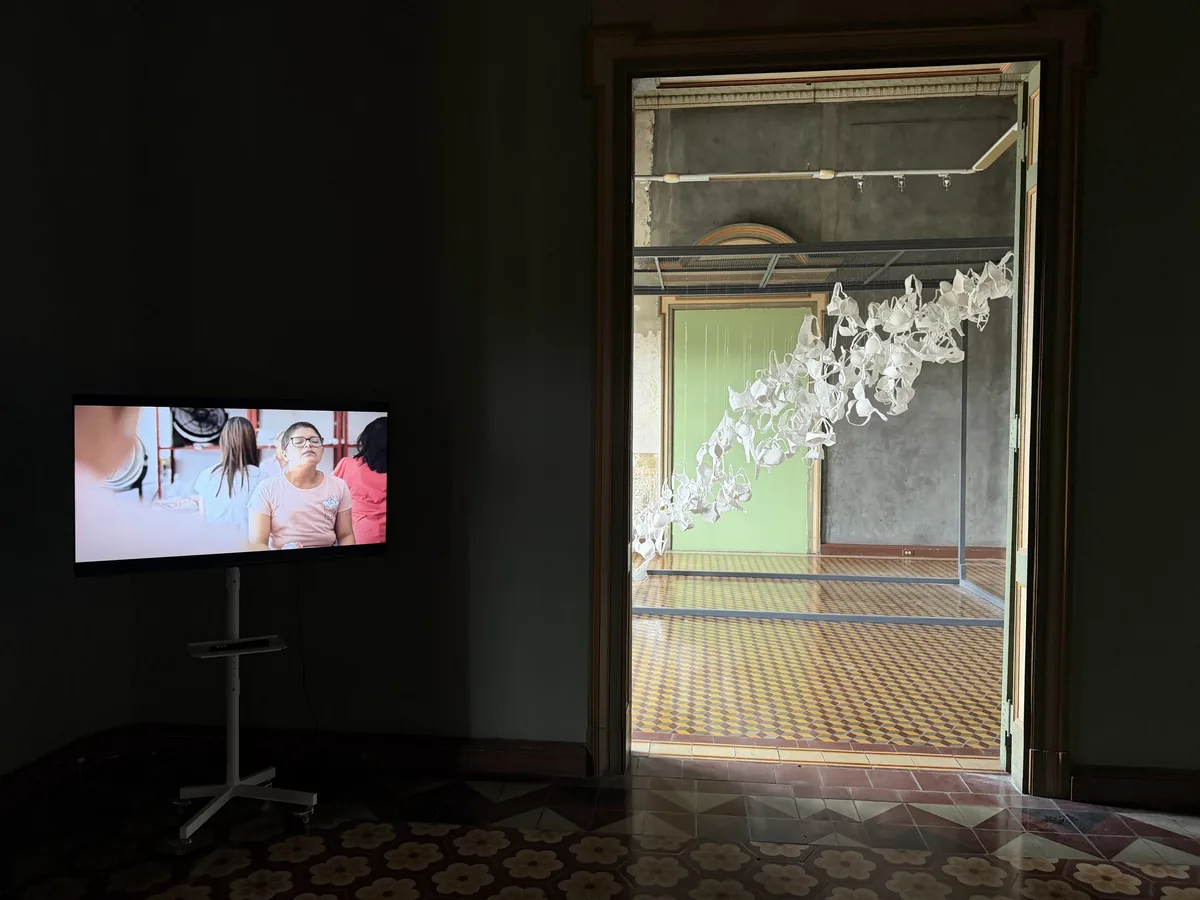 Montaje de la Sala 02 — Testimonios: pantalla de video con los testimonios y vista a través de la puerta hacia la instalación de la sala contigua